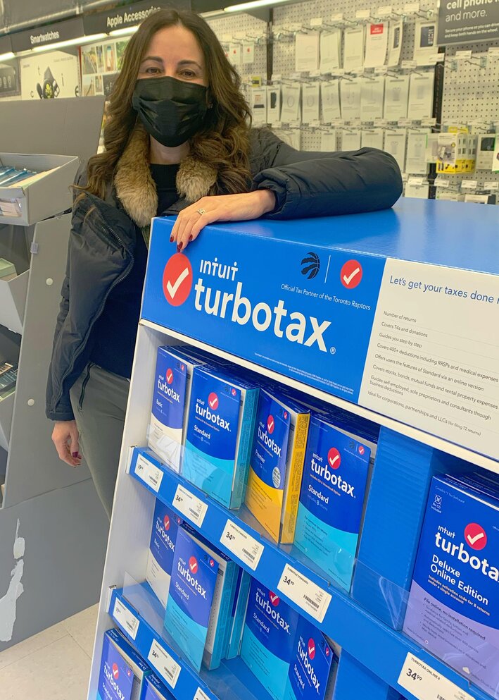 Robin standing by an Intuit Turbotax display in a Staples store.