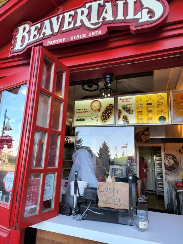 A picture of a Beavertails stand, with a cardboard poster on the cash register that says "Cash Only"
